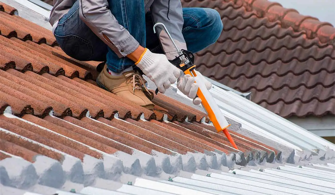Especialista profesional aplicando sellador e impermeabilizador en techo de un hogar