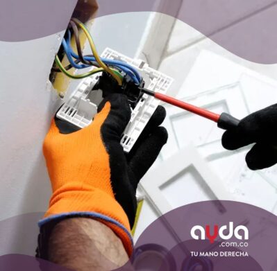 Electricista realizando instalación eléctrica de toma corriente con guantes de seguridad